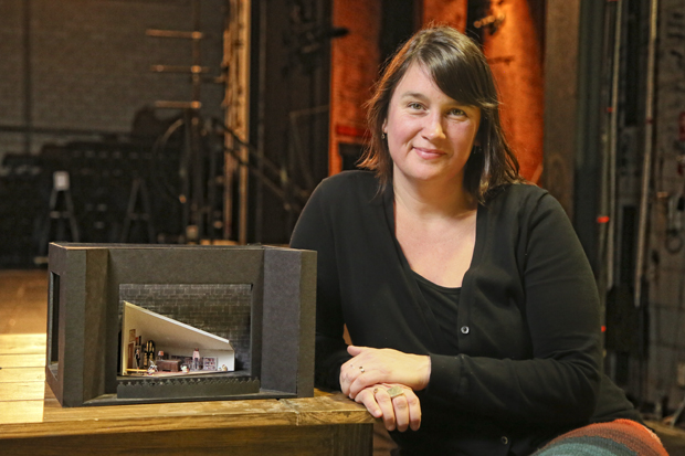 Cameron Anderson sits next to a mini model of a designed set.