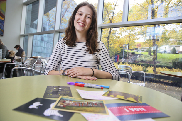 Dylan Corn with some postcards on a table in front of her.