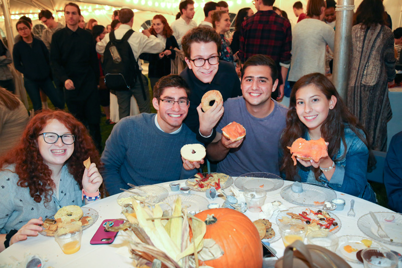 A group of students sits together eating bagels at Break the Fast