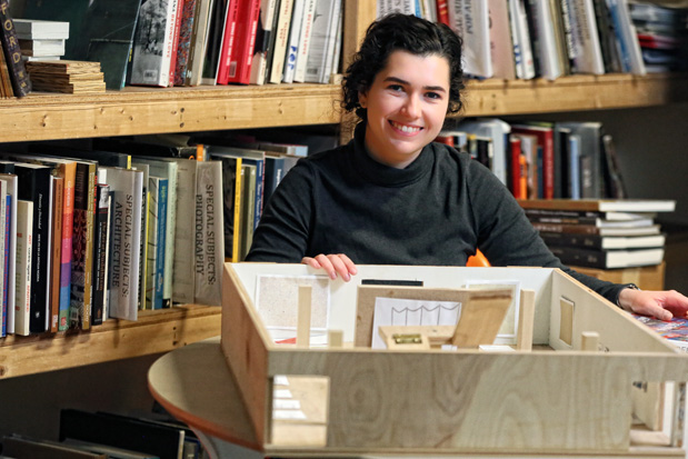 Alli Steinberg seated behind a small model used for art gallery curation