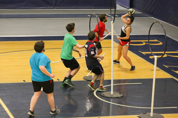 The Brandeis Quidditch team practices in Gosman. There are three vertical hoops and players hold sticks for brooms 