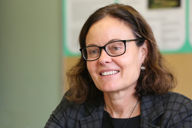 Professor of Anthropology Sarah lamb, seated wearing glasses and gray checked blazer