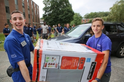 two male DCL staff carry a mini refrigerator