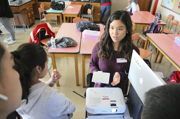 PHD student Jasmine Le shows a fruit fly experiment to high school students 