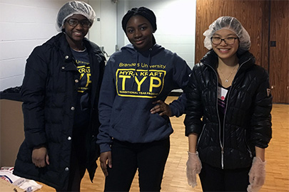 three students standing side by side after cooking a meal