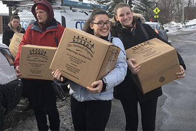 three students carrying boxes containing packed meals