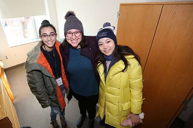 three students standing in a residence hall on move-in day