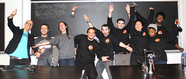 group of people dancing in front of a blackboard and behind a science table