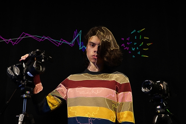 a digitally animated photo of Vicente Cayuela '22, wearing a striped sweater with two cameras against a black background