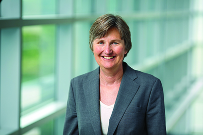 Brandeis International Business School Dean Kathryn Grady in gray suit coat against a background of windows