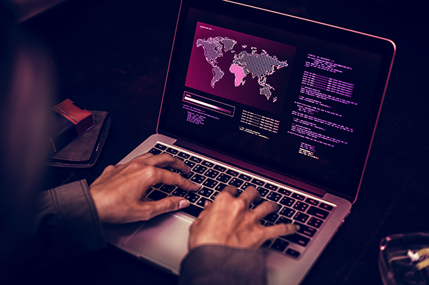 someone typing on a laptop featuring an image of the world tinted in red