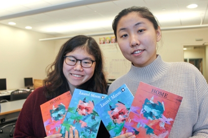 two students, in a classroom hold up copies of Laurel Moon magazine