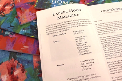 Laurel Moon Magazine open to a listing of its editorial staff, on top of a pile of covers of the magazine