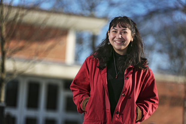 Mutiara Carney '22 in red barn jacket in front of a campus building