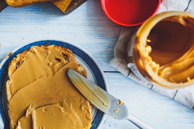 knife spreading peanut butter on toast