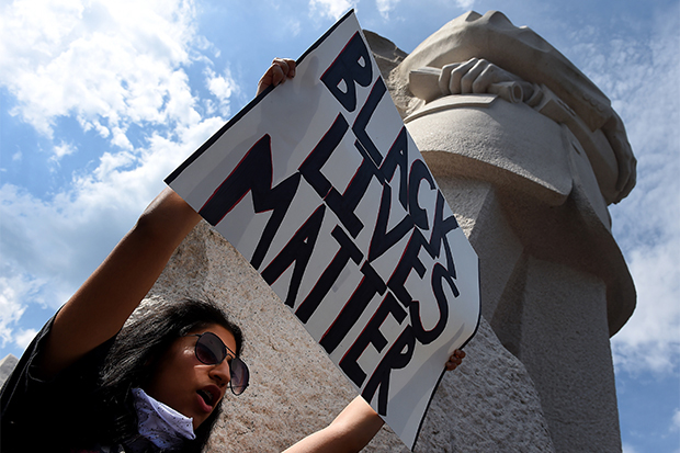 A woman holds up a Black Lives Matter sign at the foot of the Dr. Martin Luther King Jr. memorial statue in Washington.