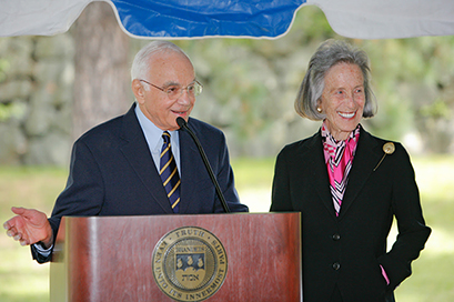 the late Morton Mandel and his wife Barbara Mandel, both in black suits, at a podium under an awning during the opening of the Mandel Center for the Humanities