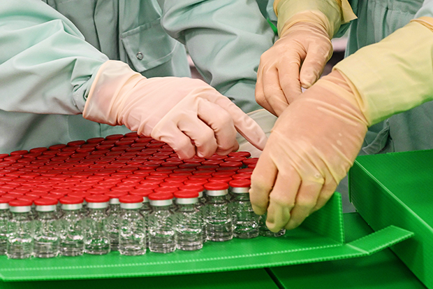 Gloved hands handle vials of vaccine