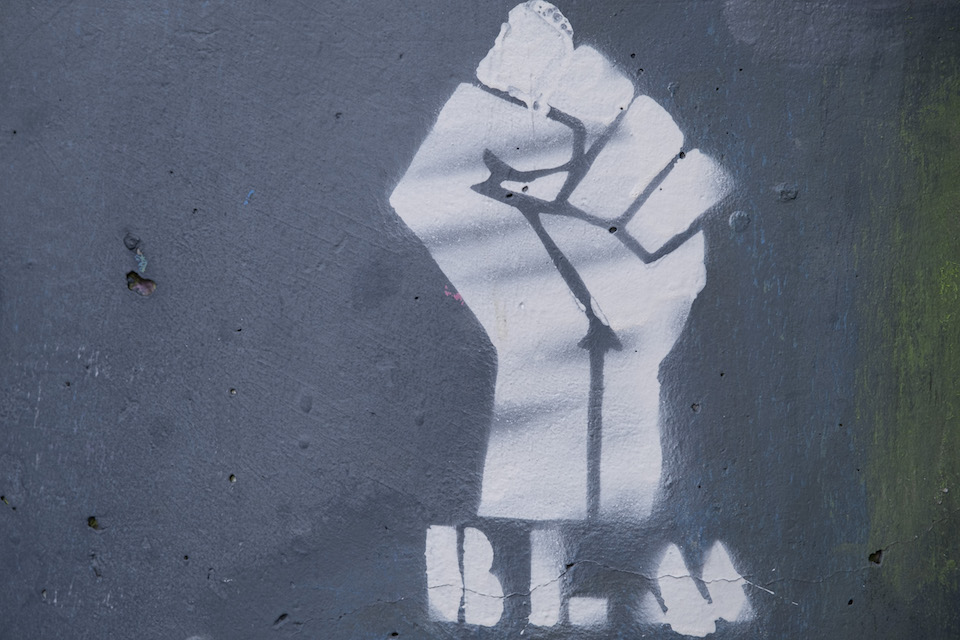 A spray painted raised fist with BLM underneath on concrete