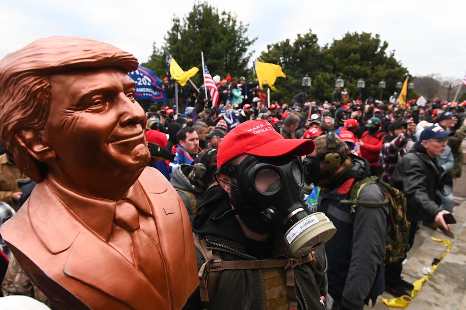 A supporter of US President Donald Trump wears a gas mask and holds a bust of him outside the Capitol building on January 6