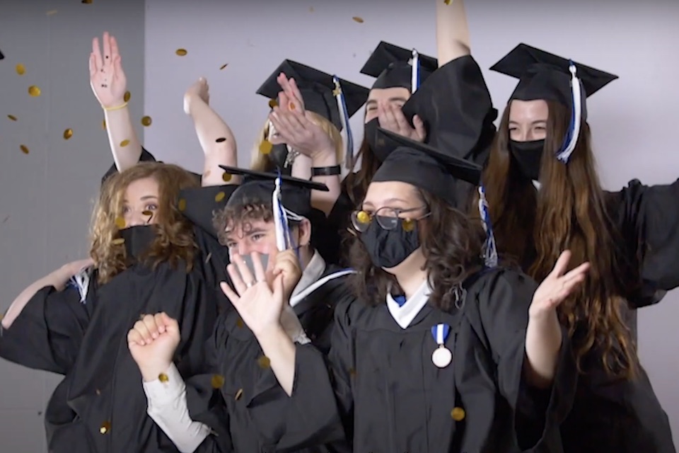 A group of celebratory students in regalia pose for a photo