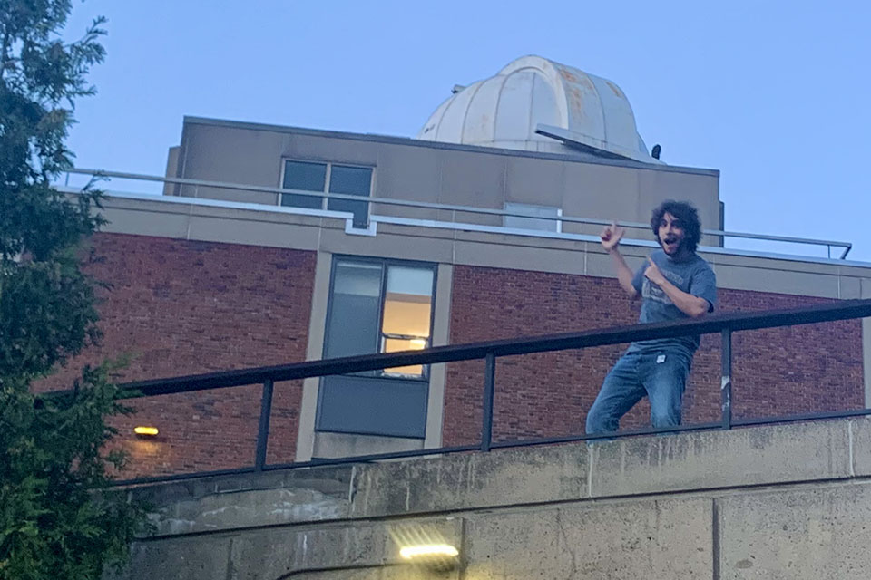 Mark Rozencwaig pointing to the observatory dome from a nearby roof