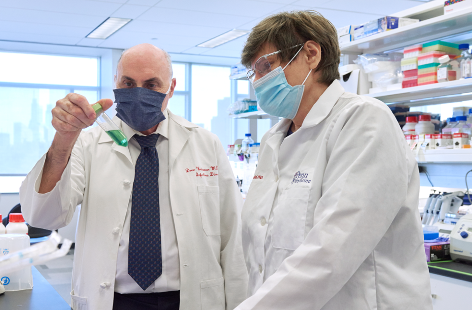 Drew Weissman ’81, MA ’81, and collaborator Katalin Kariko in lab coats and masked looking at a test tube in the lab