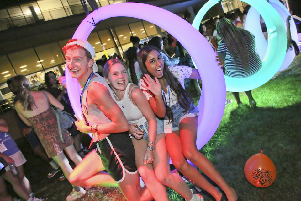 Three students smiling, sitting on a light up swing
