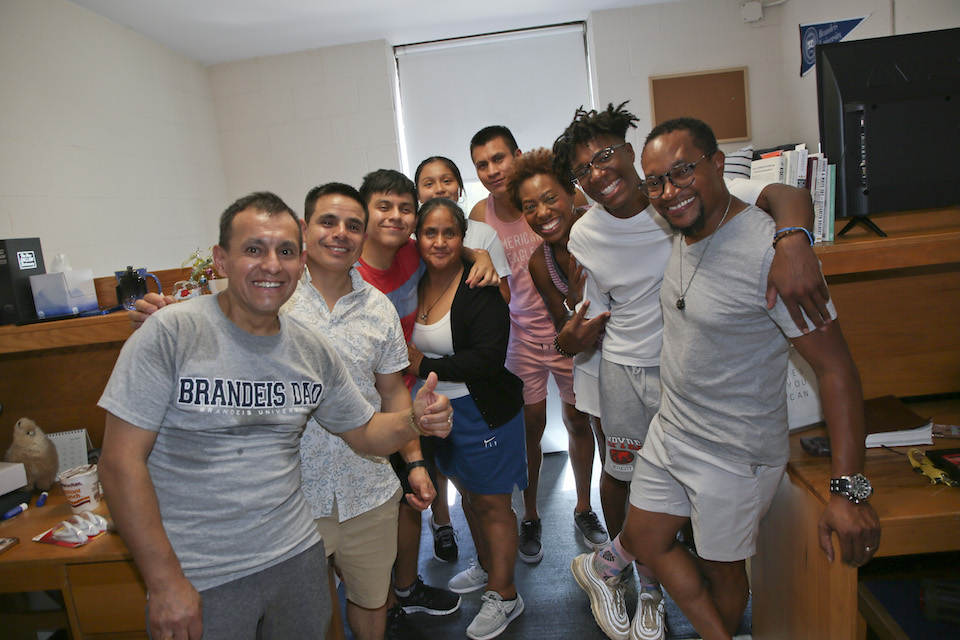 Two roommates and their families pose for the camera in the room