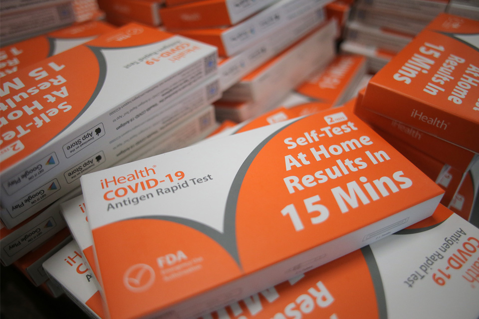 stacks of orange and white COVID test boxes that say "iHealth Covid-19 Rapid Antigen Test" "Self-Test at home results in 15 minutes" 