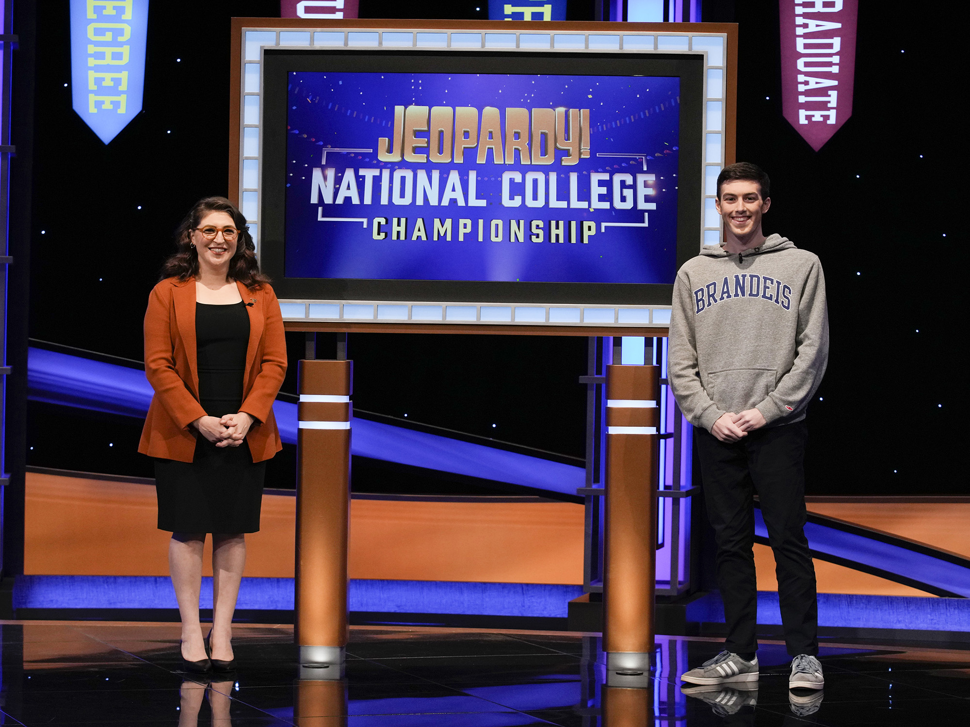 joey kornman poses in front of the jeapordy sign with host