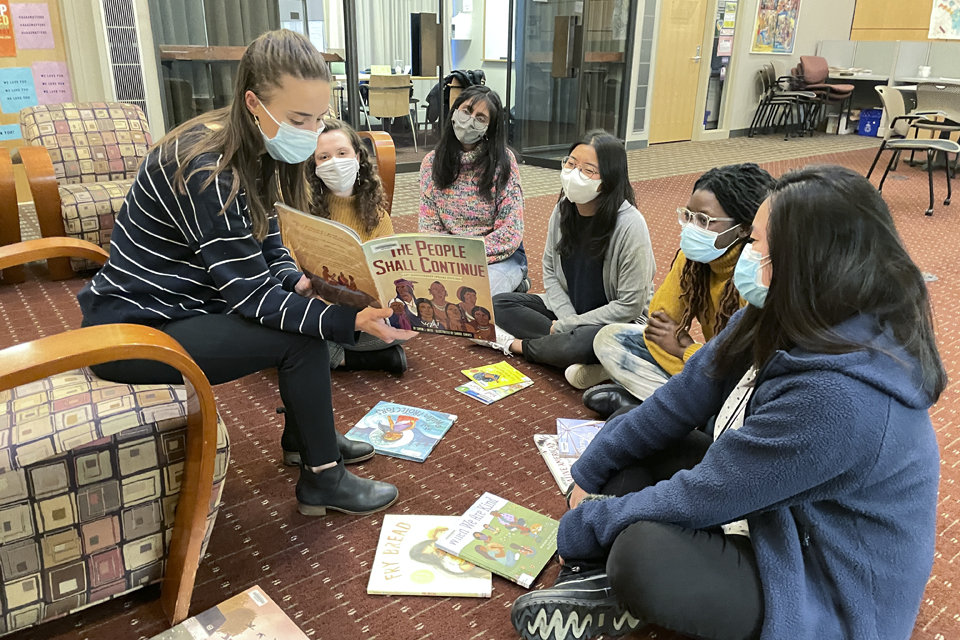 students in the Elementary Teaching and Learning 3: Literacy course gather around a classmate reading