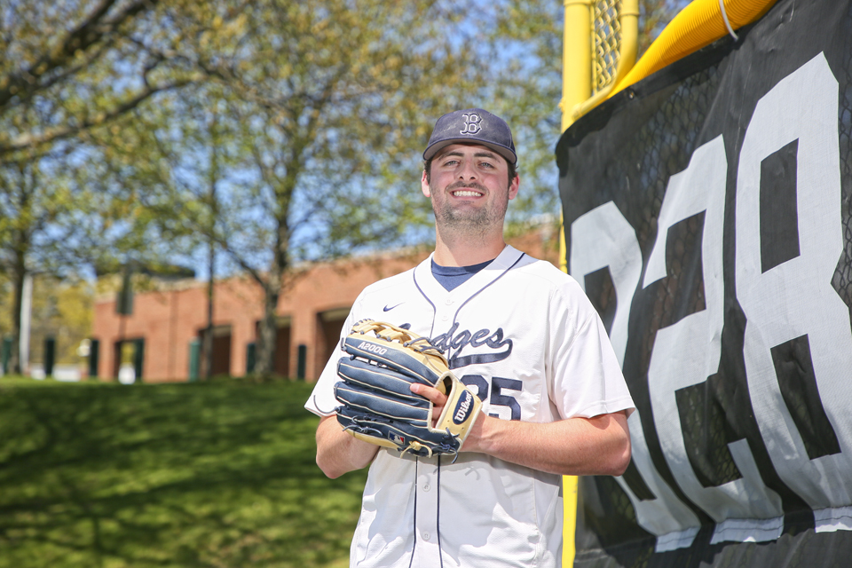 Mike Khoury poses while wearing a baseball glove and uniform