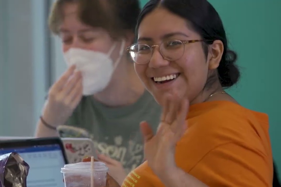 Student waiving at camera