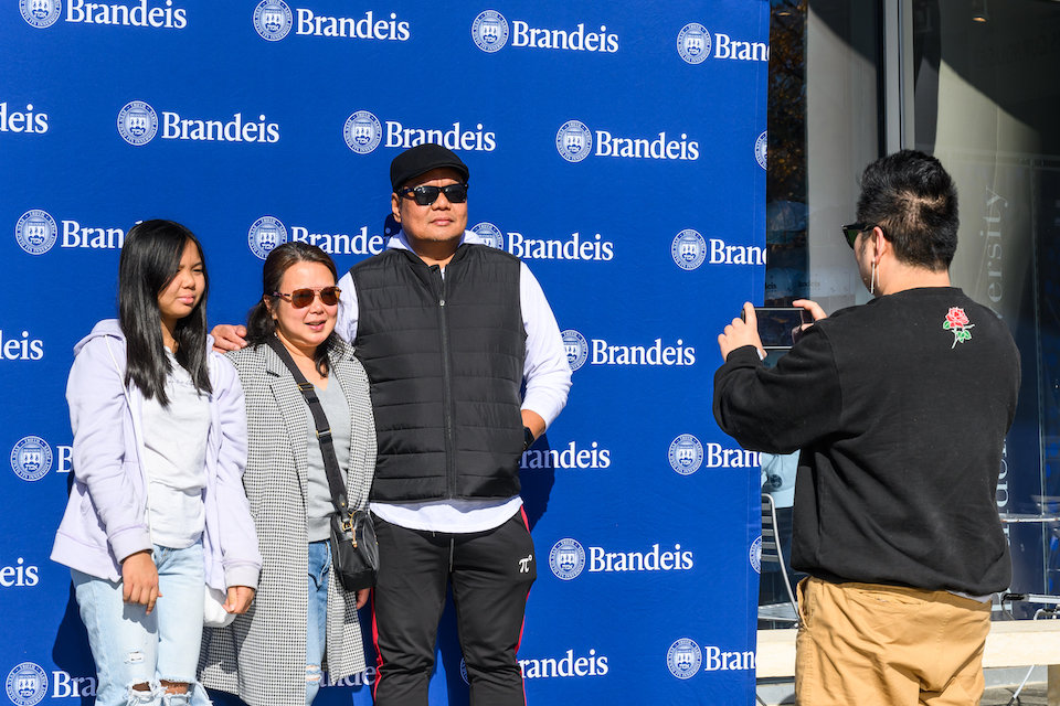 A student poses for a photo with family in front of a Brandeis banner