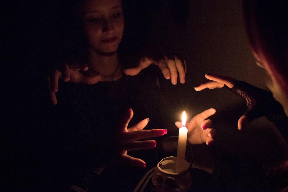 A group of people hold their hands out around a burning candle