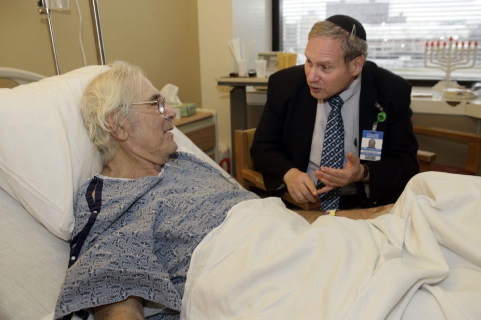 A chaplain speaks to a hospital patient.