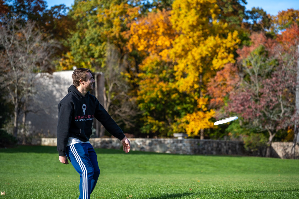 campus foliage and student throwing frisbee