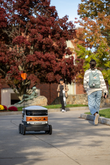 Delivery robot on a path with foliage in background