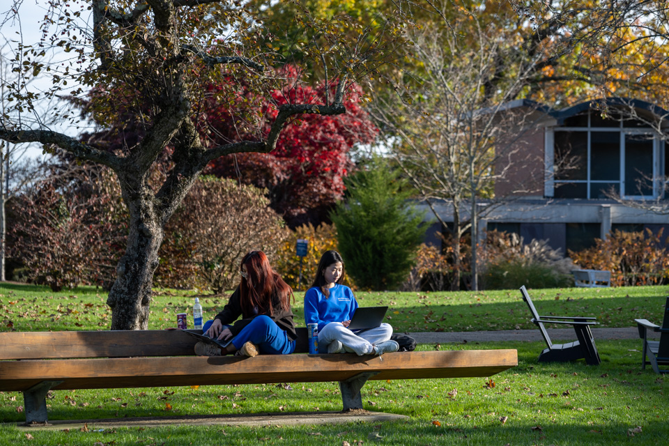 Students sit on bench in fellows garden