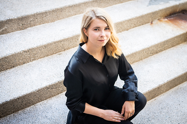Sofiia Tarasuik sitting on concrete steps, wearing a black shirt and black pants