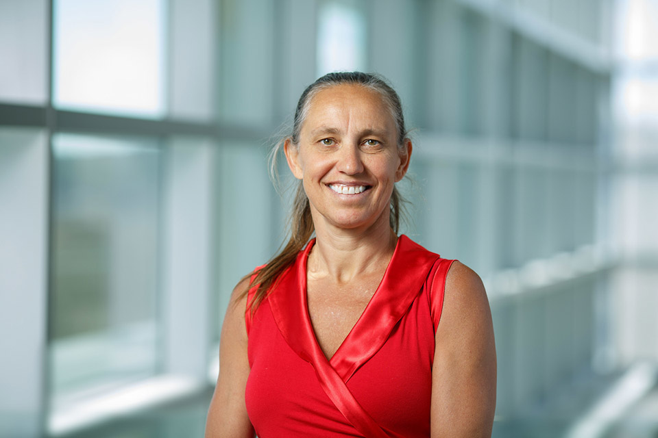 Professor Dorothee Kern standing in a hallway in a red sleeveless shirt