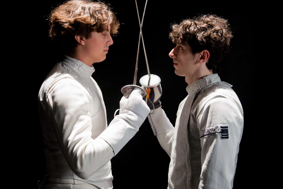 Two fencers face each other, holding foils.