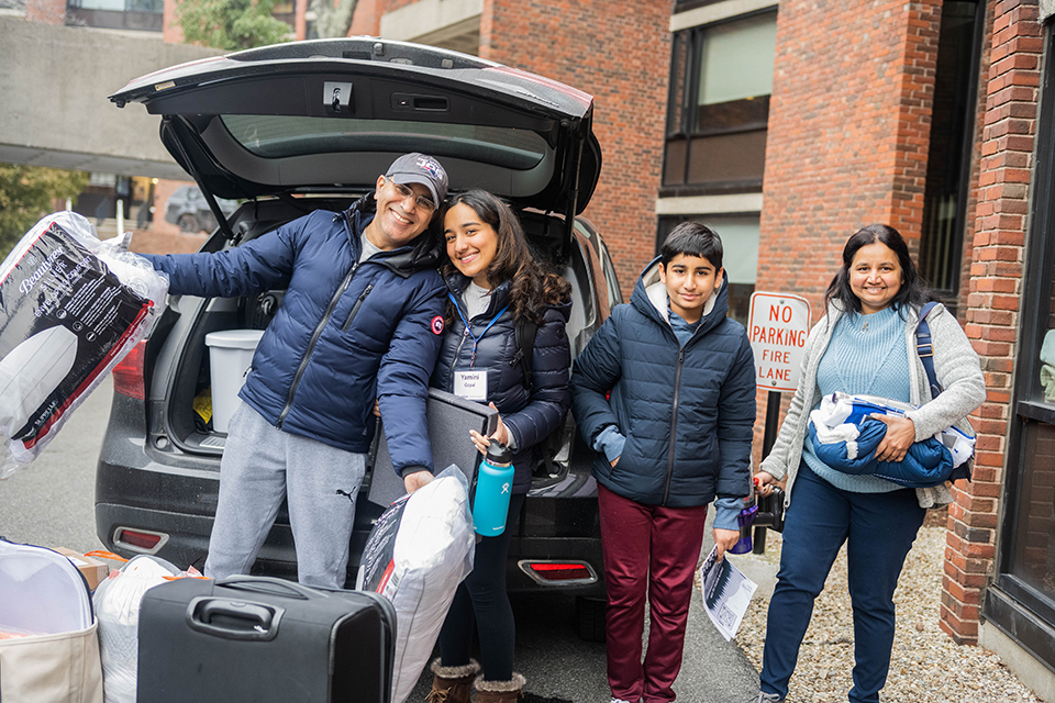 family of four poses at car