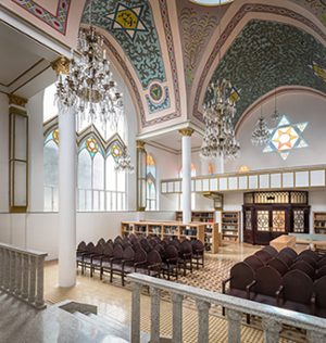 The interior of the Rodfe Sedek synagogue in Mexico, with arched ceilings, chandelieres, and pews.