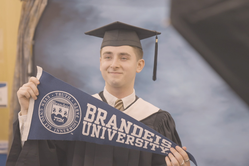 A student holds up a Brandeis pennant