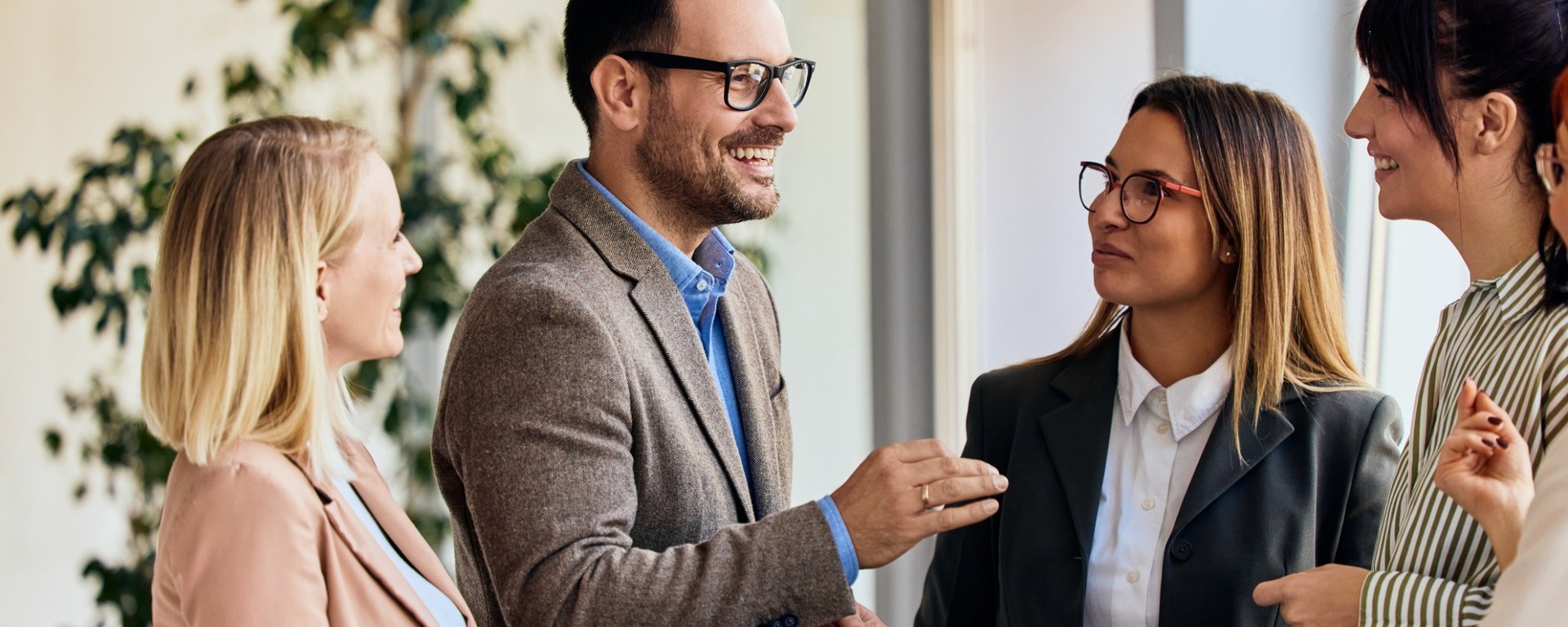 four working professionals speaking to one another in a hallway 
