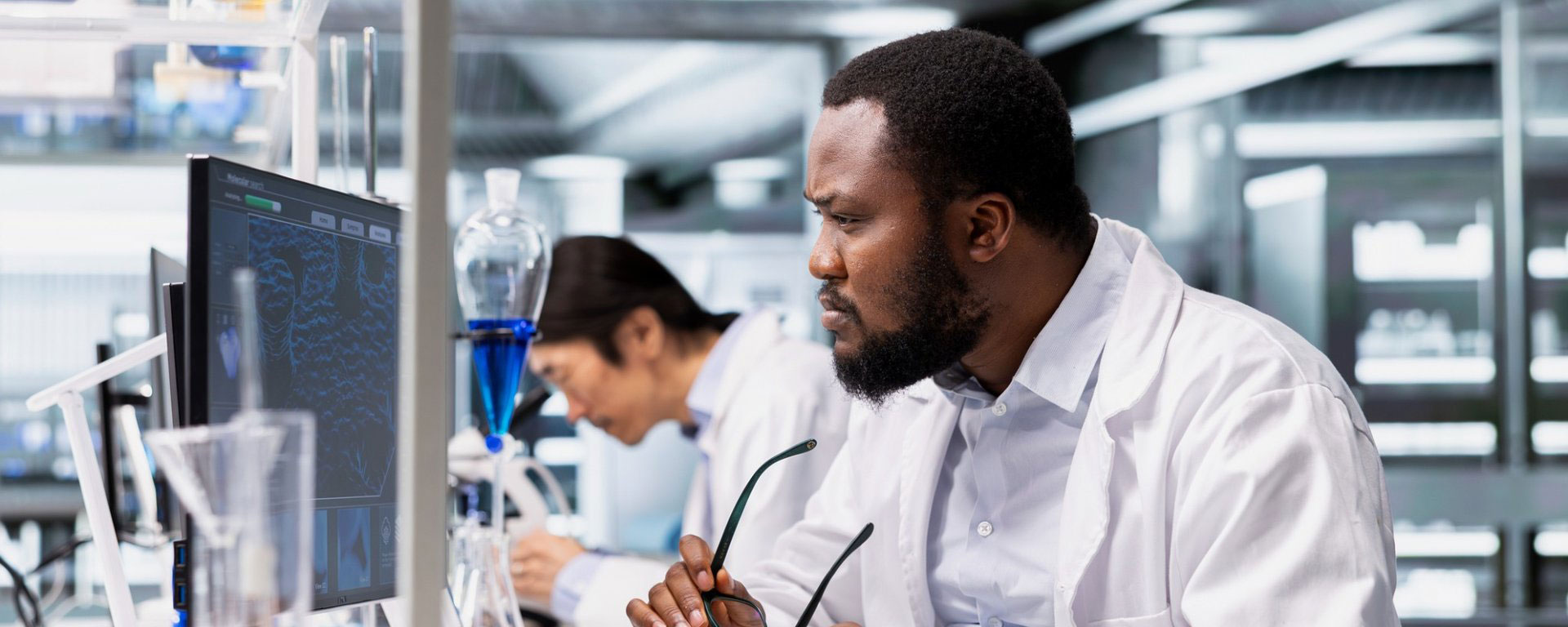 scientist sitting with glasses in hands looking at computer screen
