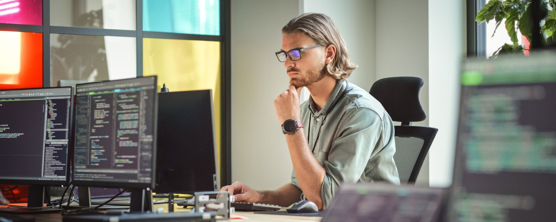 Man works behind a desk on a large computer screen