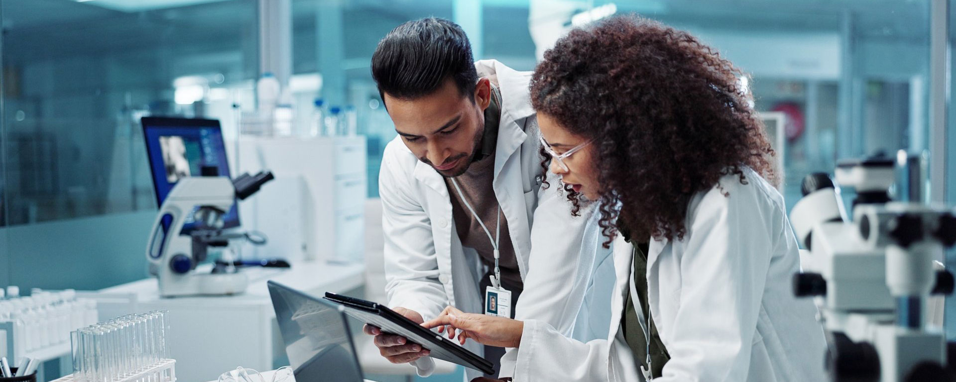 Two scientists in a lab looking at a tablet